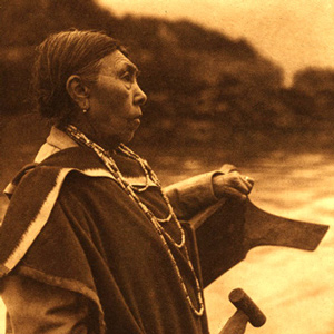Woman holding paddle standing at the bow of a canoe