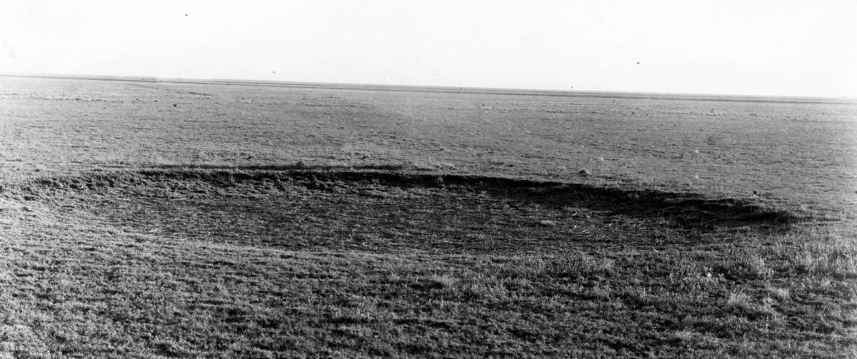 large circular depression in a barren prairie
